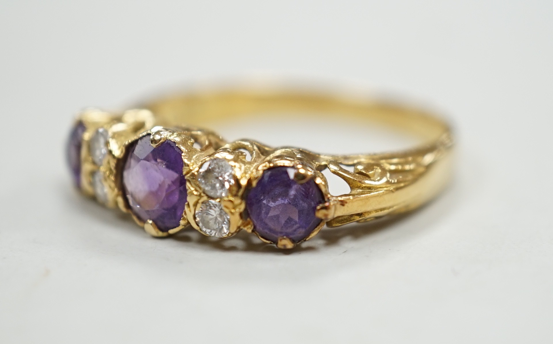 An 18ct, three stone amethyst and four stone diamond set half hoop ring, size Q/R, gross weight 4 grams.